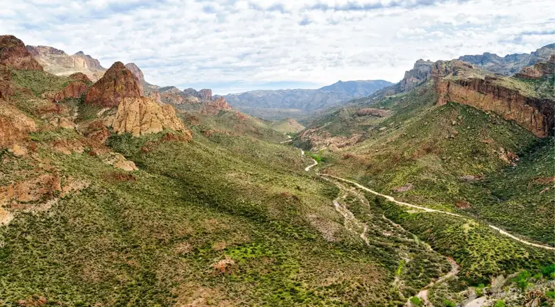 Aerial view of the Apache Trail winding through a green desert canyon