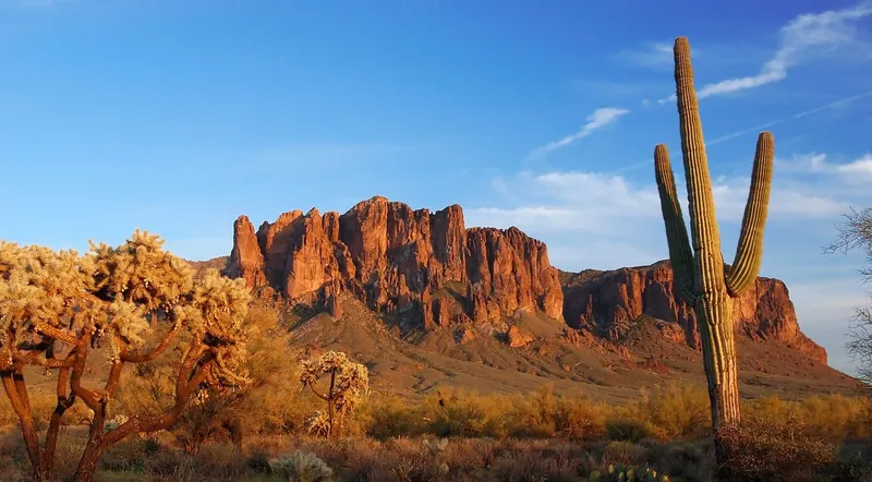 Superstition Mountains rock formations with cholla cactus in daylight